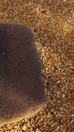 Close up of a large brown stone set in amongst smaller orangey-tan pebbles