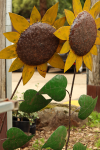 Decorative metal sunflowers with brown centers and yellow petals on a blurred outdoor background.