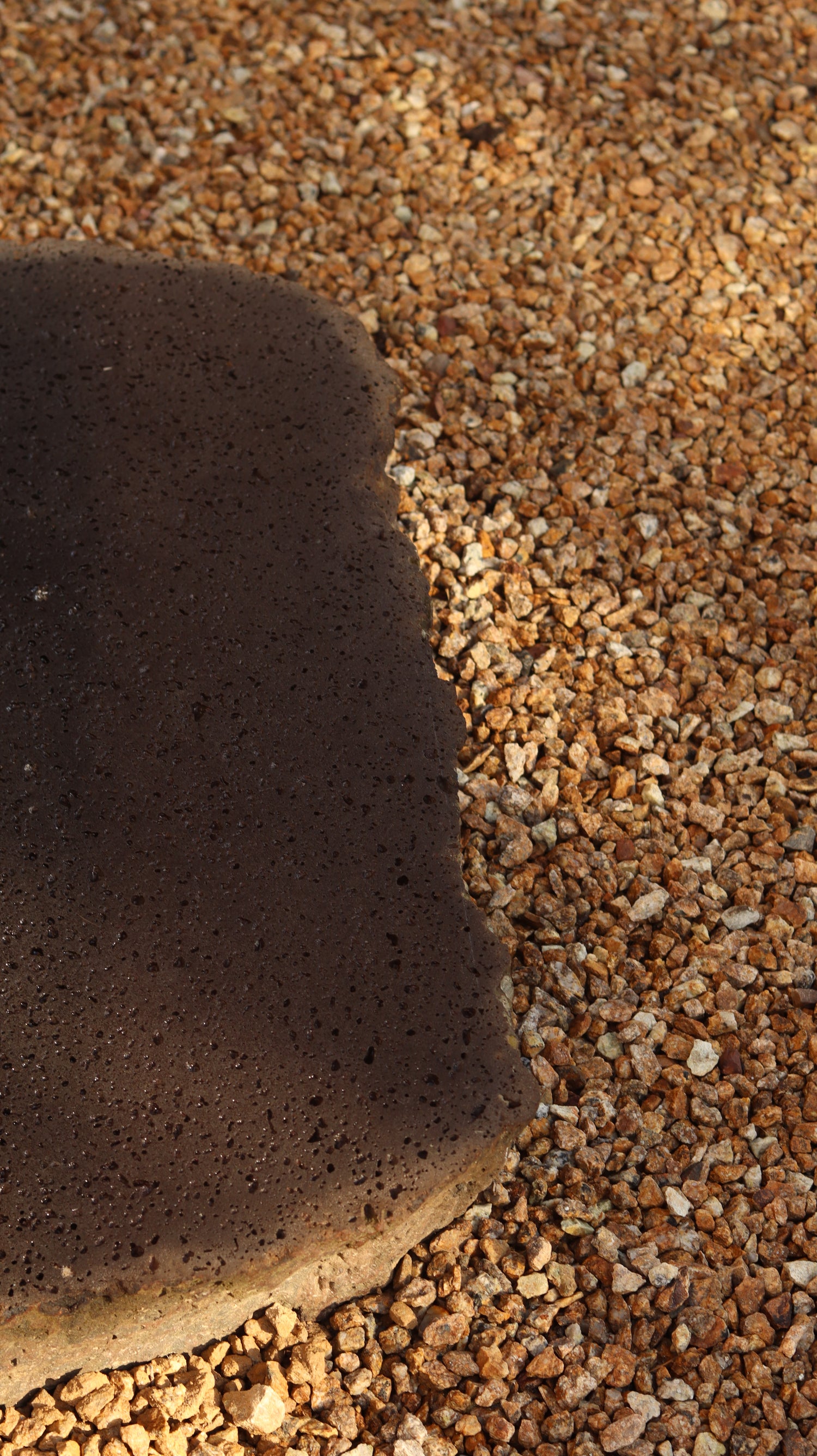 Close-up of a basalt rock on a textured brown surface