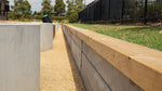 Concrete and wooden retaining walls with a decorative concrete path in an outdoor setting.