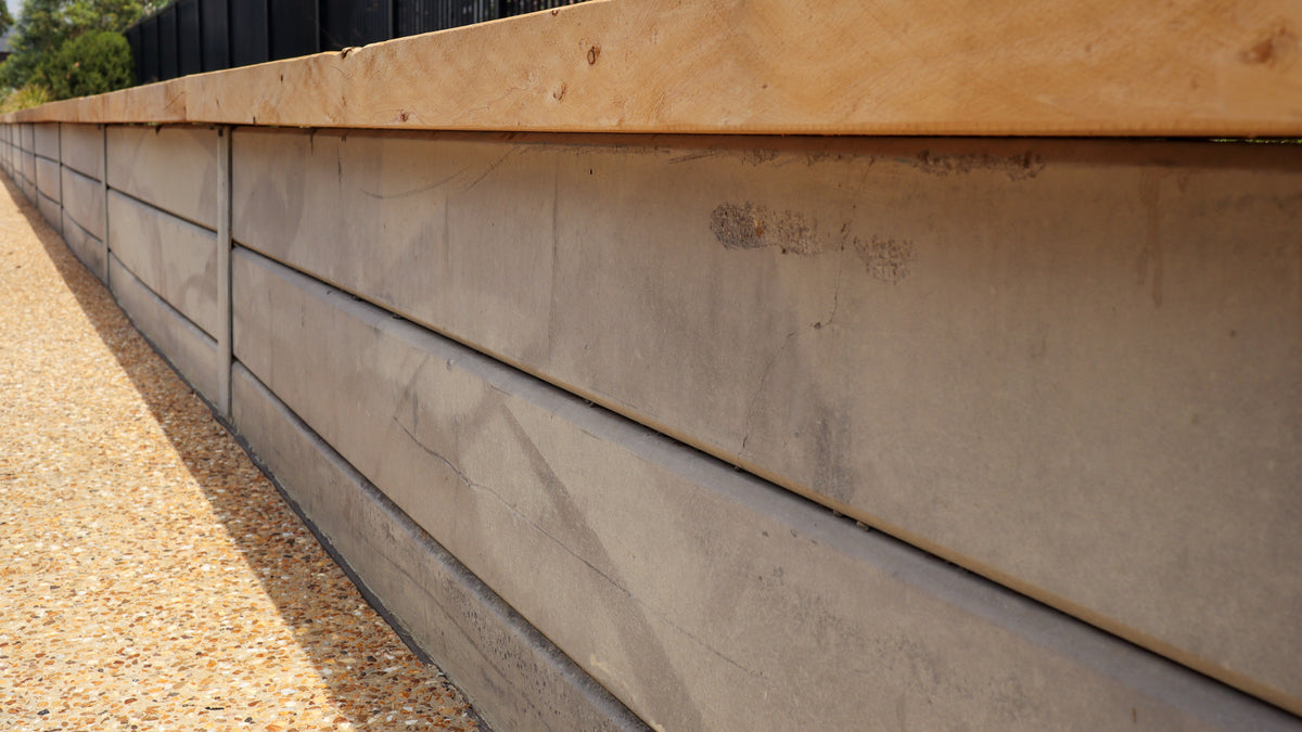 Concrete retaining wall with wooden top section on a sunny day