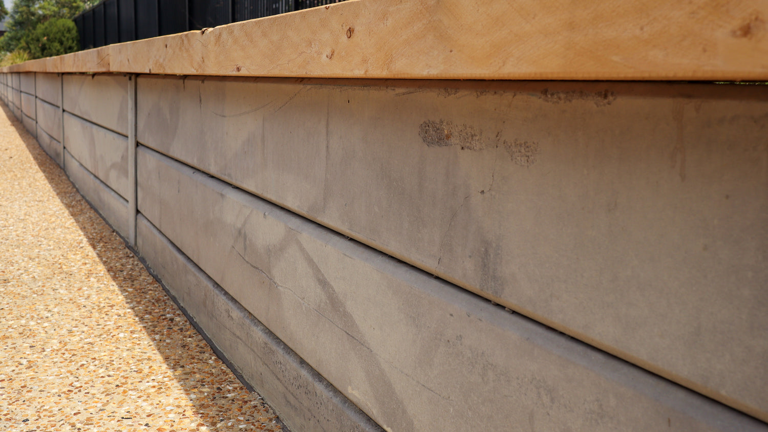 Concrete retaining wall with wooden top section on a sunny day