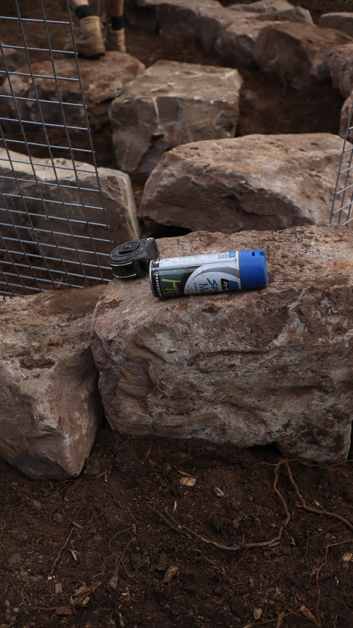 A blue marking paint can lays on a mudstone rock