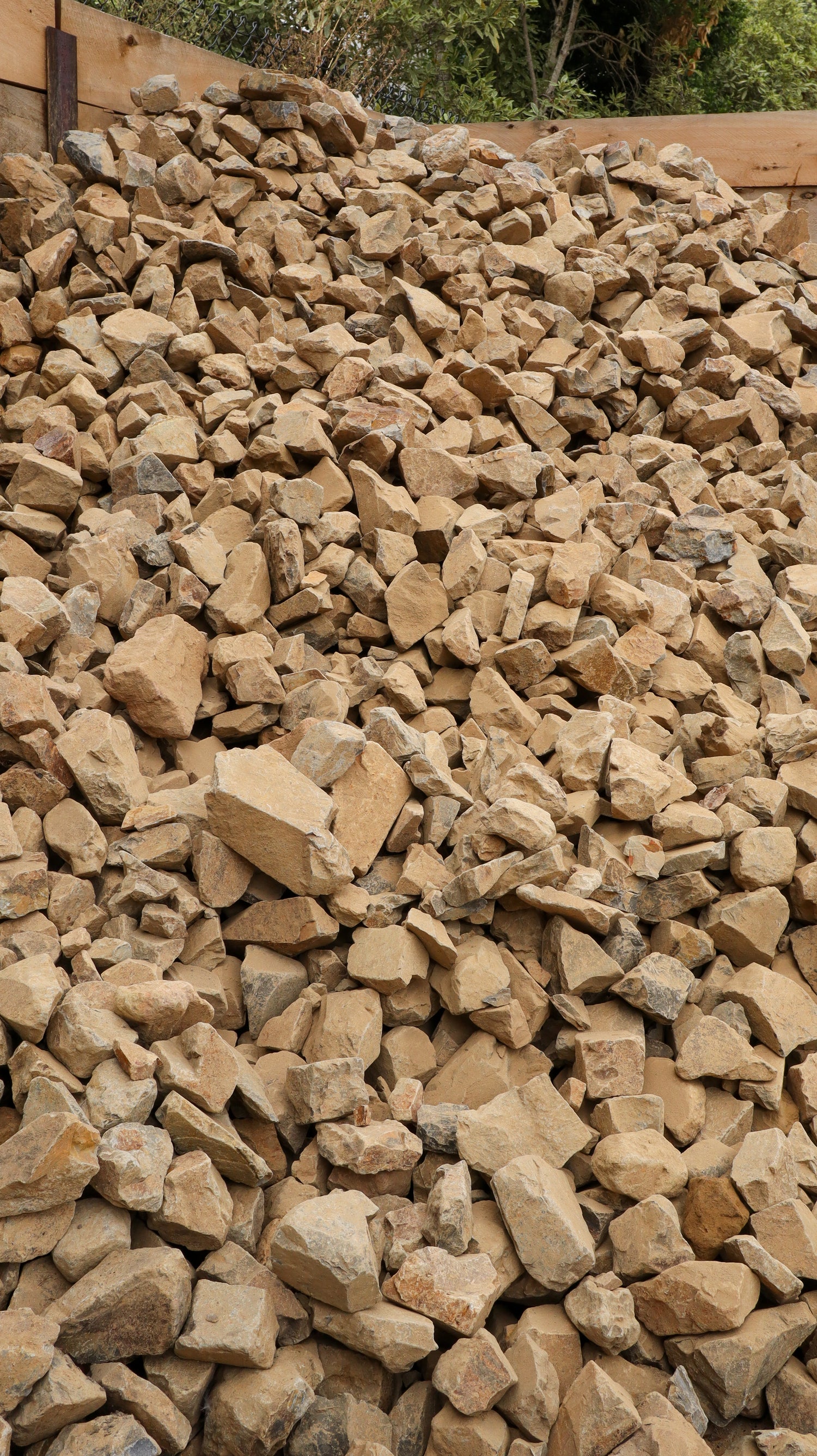 Pile of stones with a wooden structure and greenery in the background