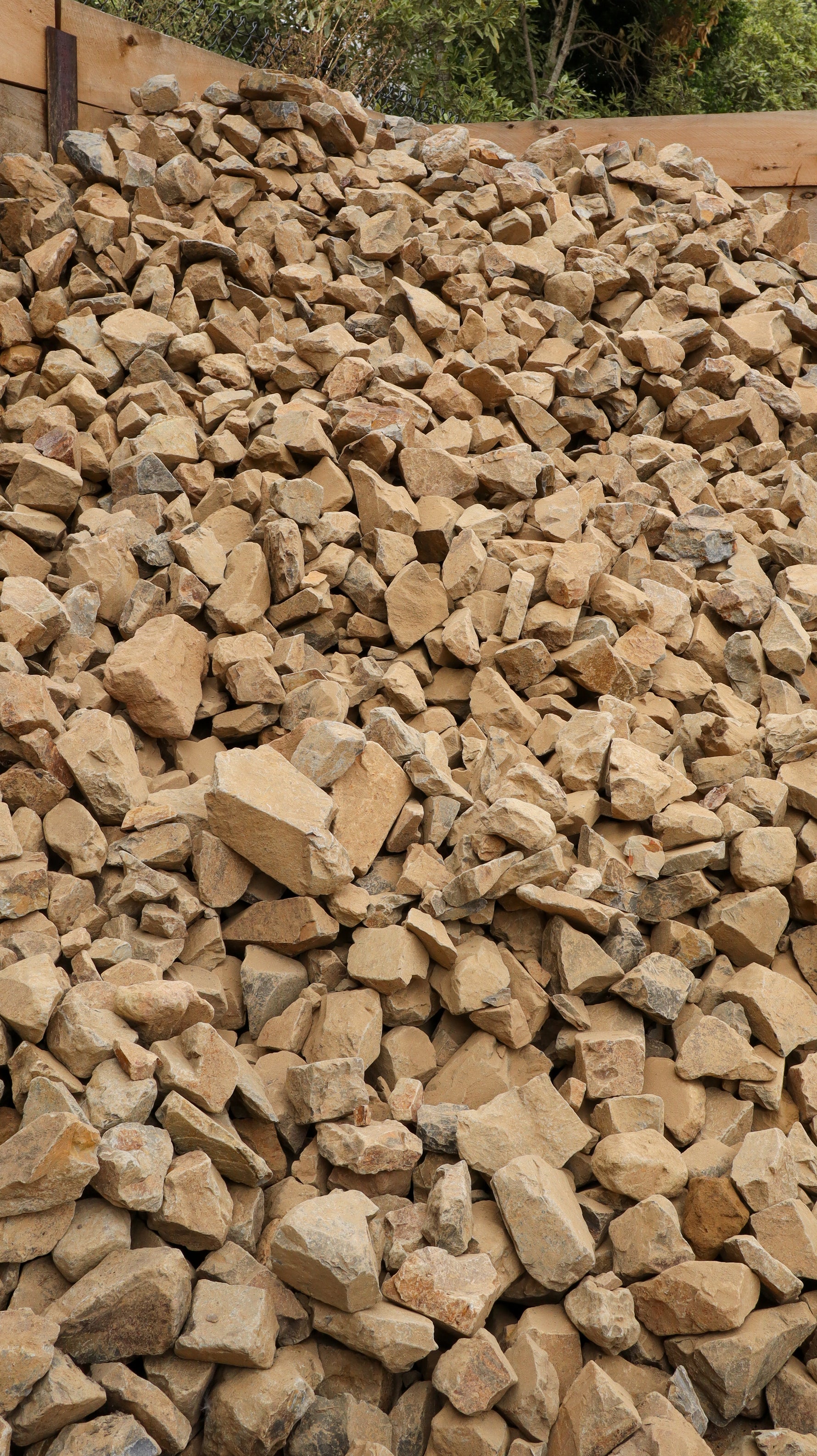 Pile of stones with a wooden structure and greenery in the background