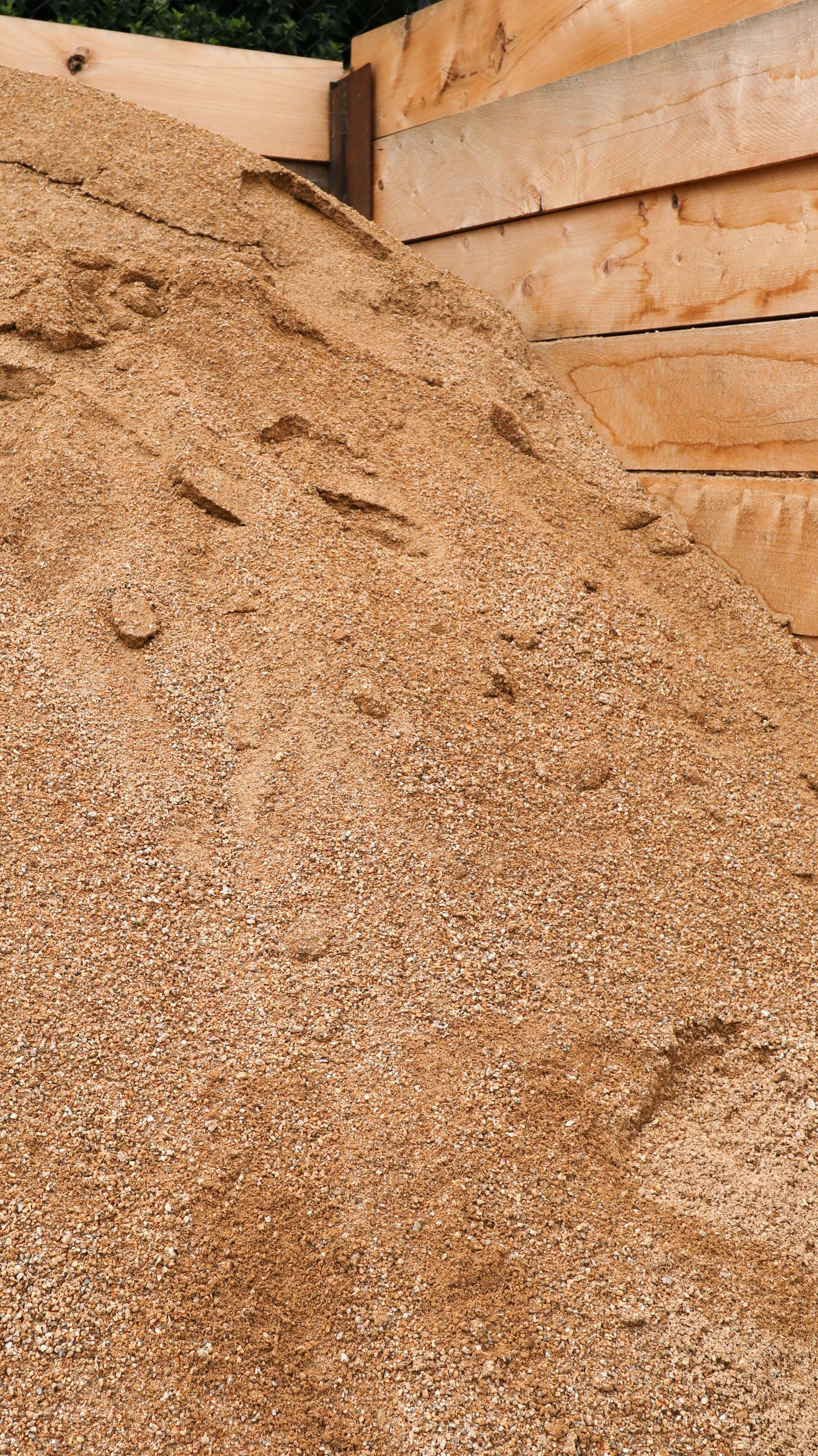Close-up of a pile of granitic sand with wooden planks in the background