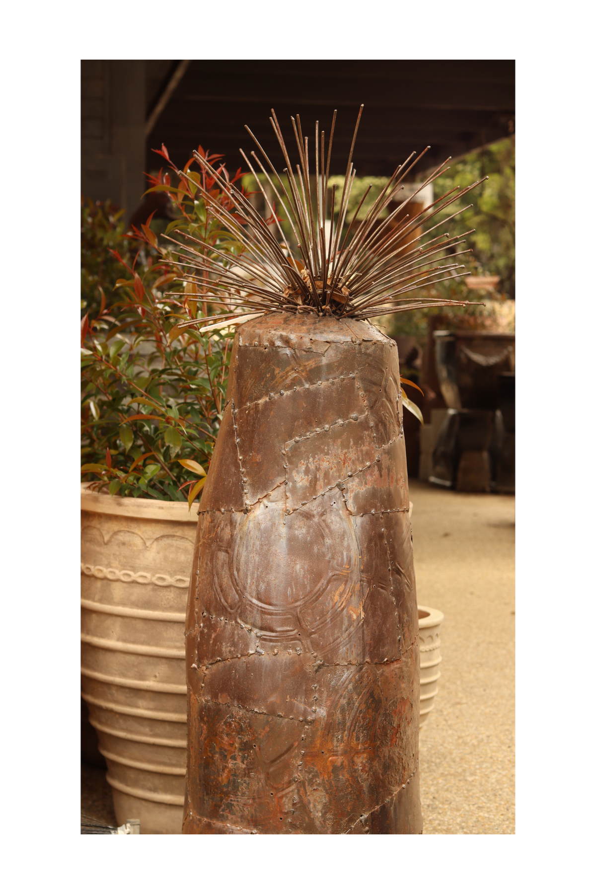 A rustic metal sculpture of a grass tree on a decorative background