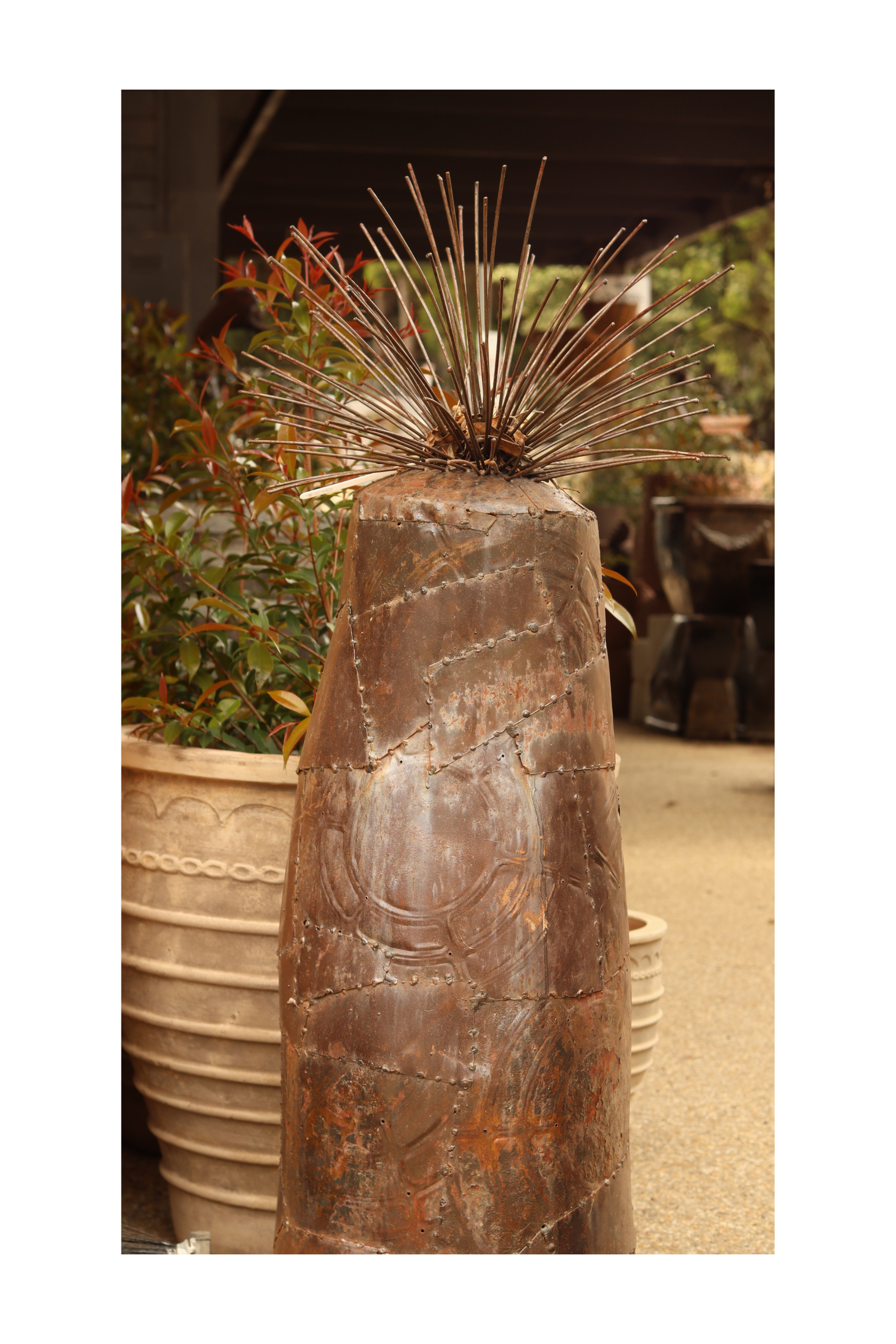 A rustic metal sculpture of a grass tree on a decorative background