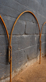 Rustic steel bent into hoops against dark blue brick background