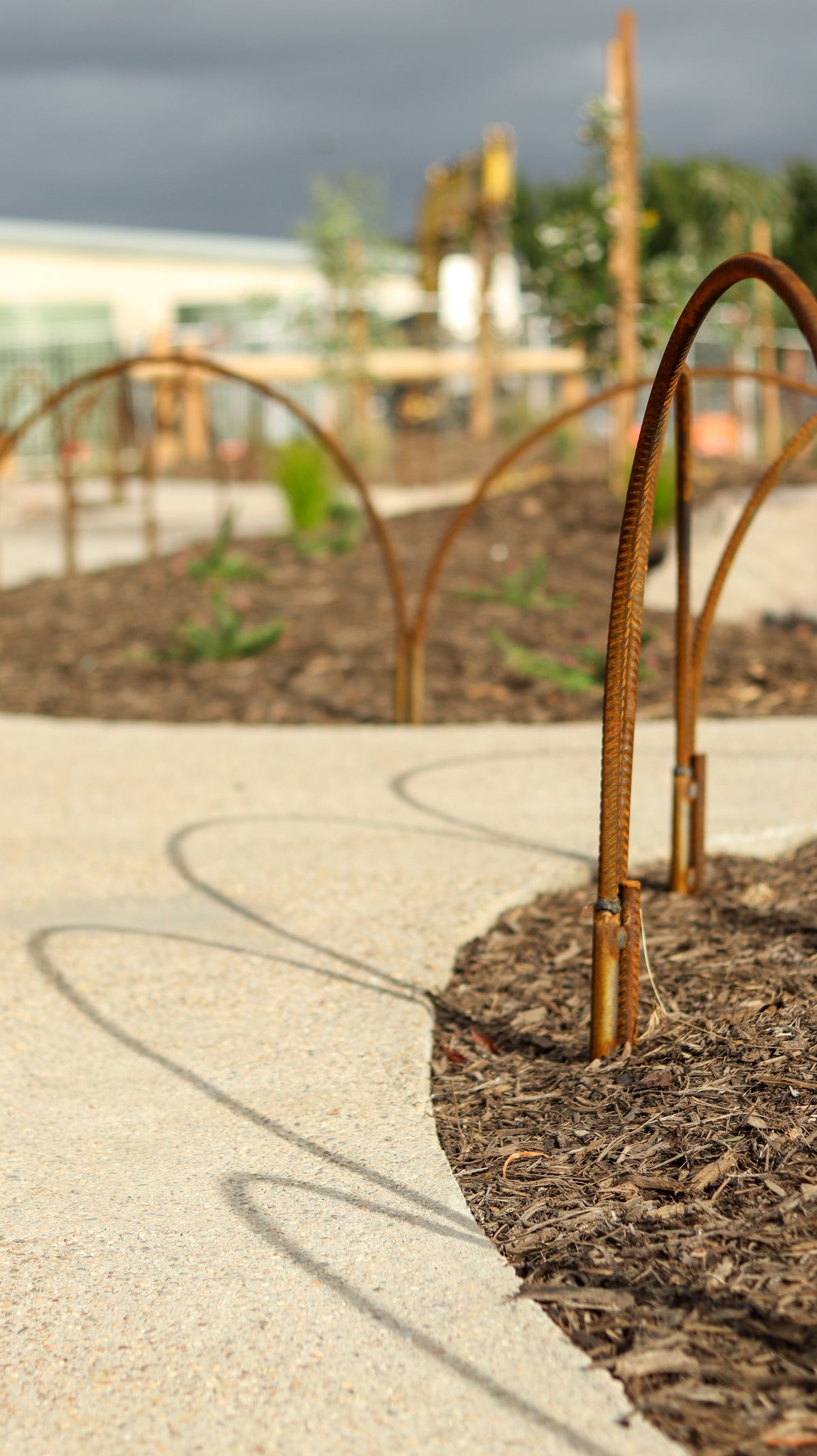 Rust-colored metal hoop along a concrete path with blurred background