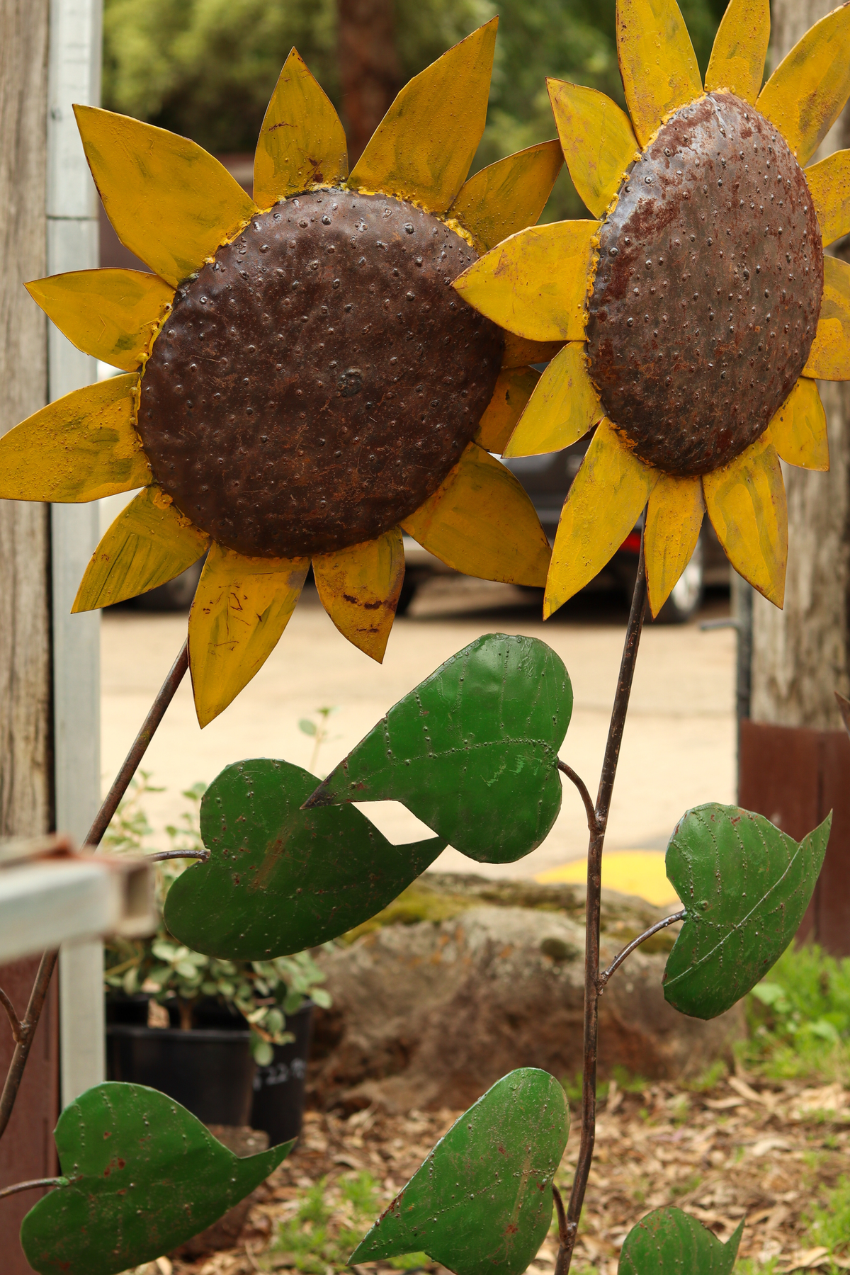 Decorative metal sunflowers with brown centers and yellow petals on a blurred outdoor background.